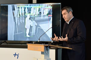 Bild vergrößern: Ministerpräsident Markus Söder bei seiner Ansprache - im Hintergrund auf dem Bildschirm von der KI in Echtzeit registriert